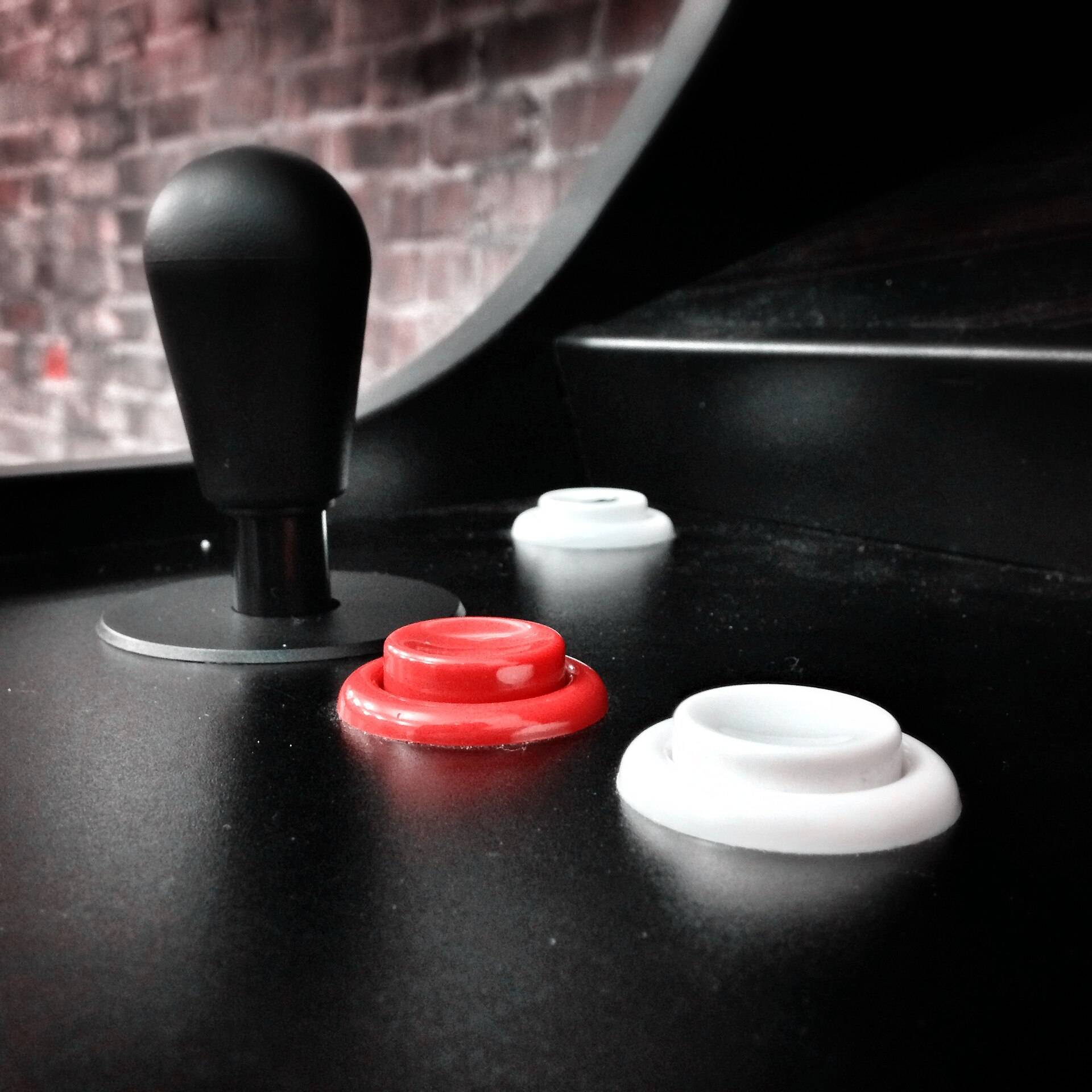 An arcade joystick and its buttons on a black cabinet, close