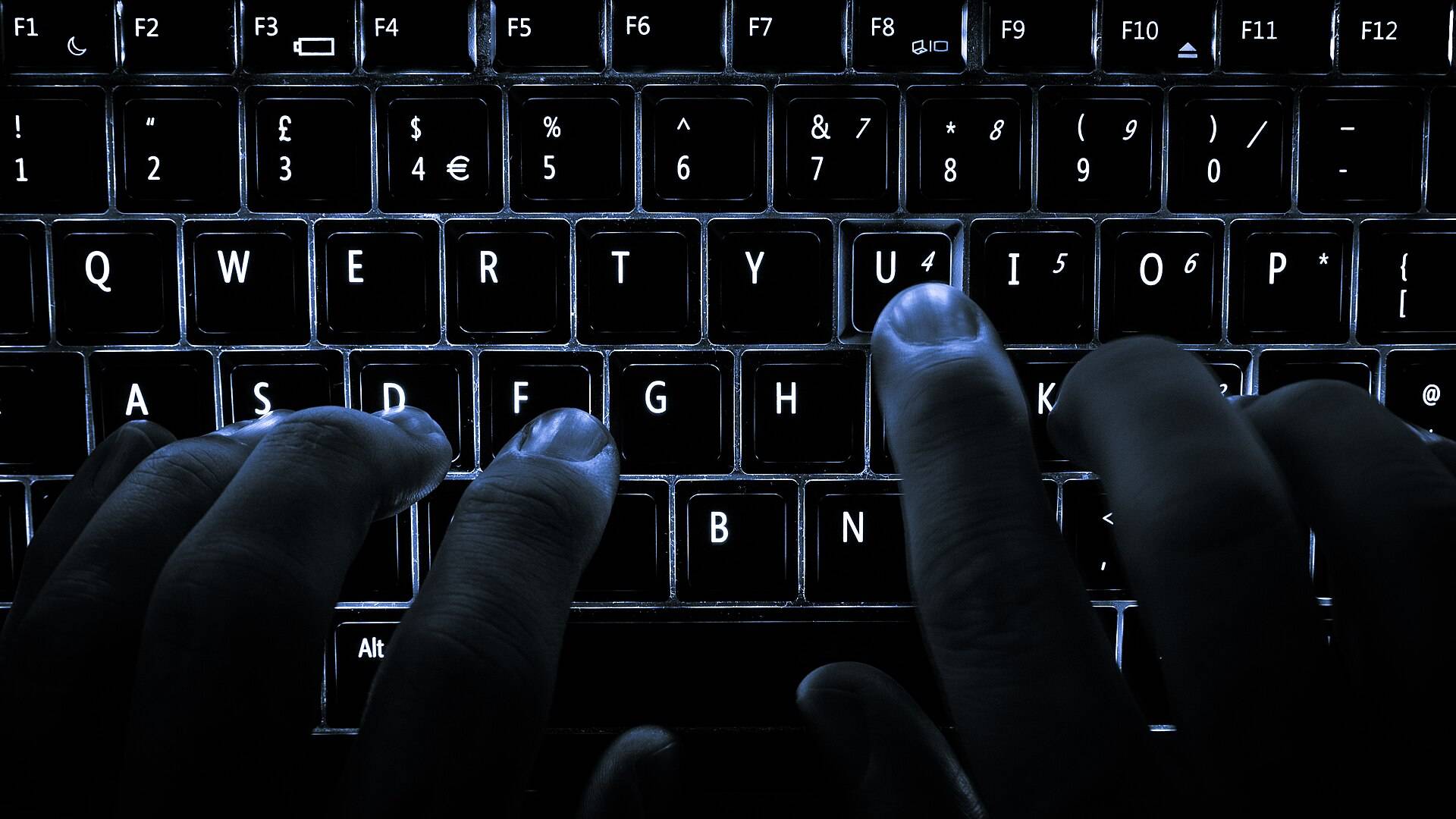 Fingers on a backlit keyboard in the dark