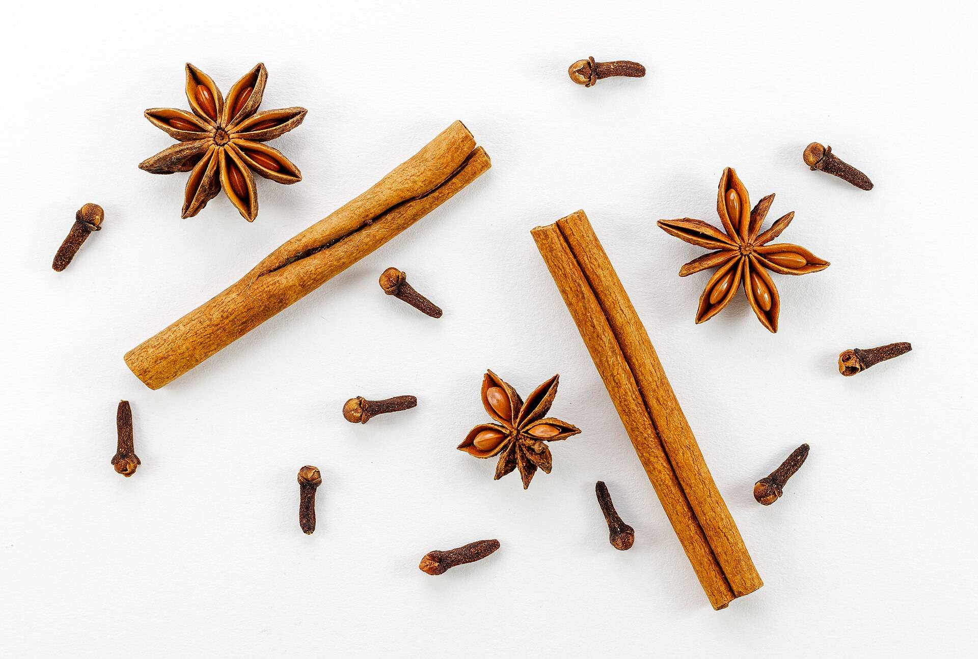 Star anise, cinnamon sticks and cloves scattered on a white ground