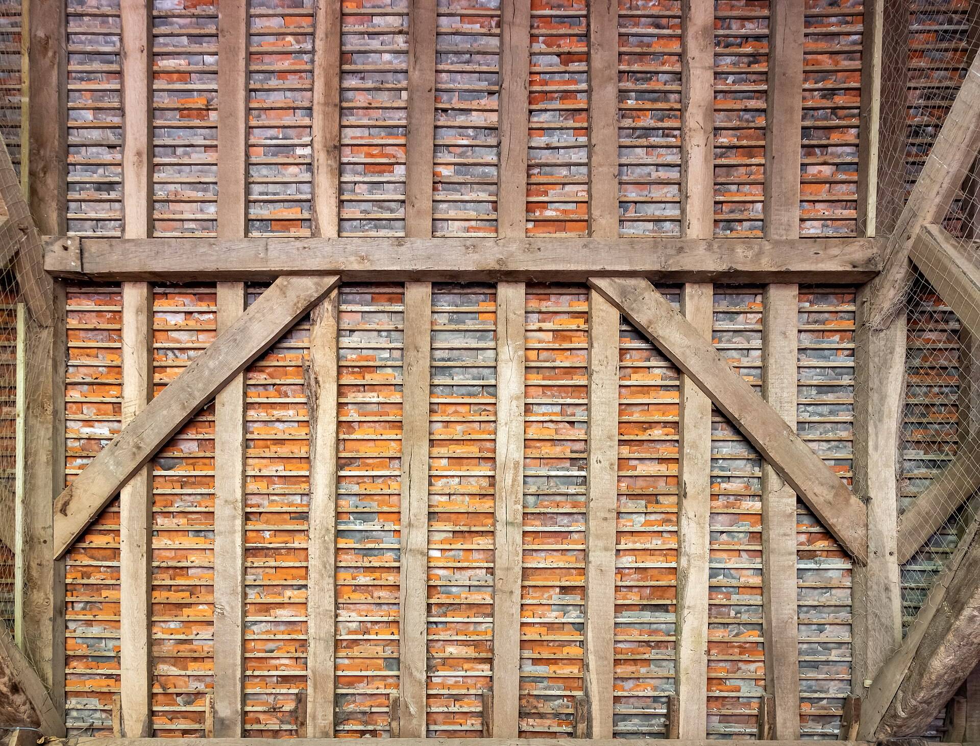 A timber frame wall of posts, rails and two long braces, seen square-on