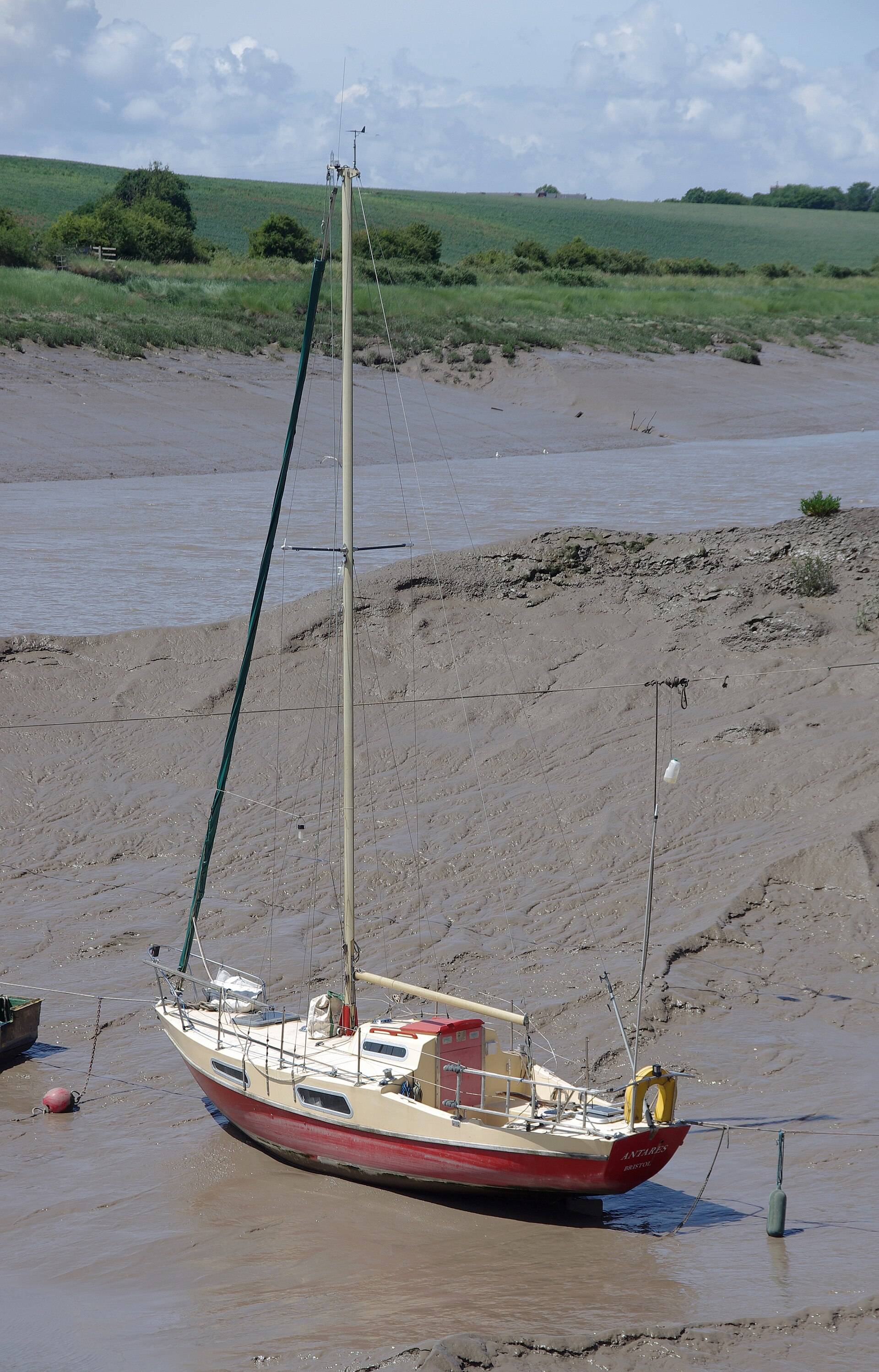 A small sailing boat resting on a mud bank in a tidal river at low water