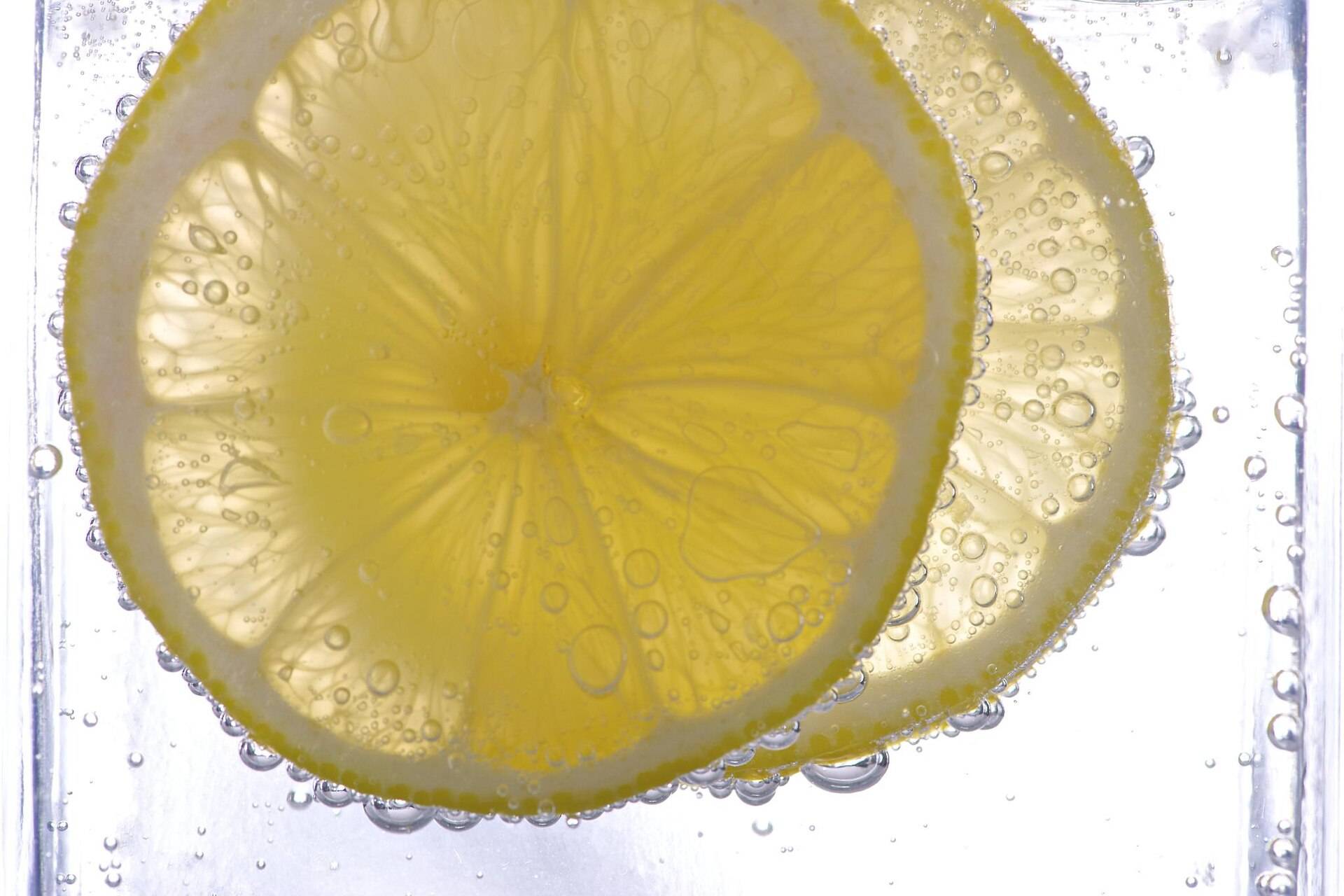 Two lemon slices suspended in sparkling water among tiny bubbles