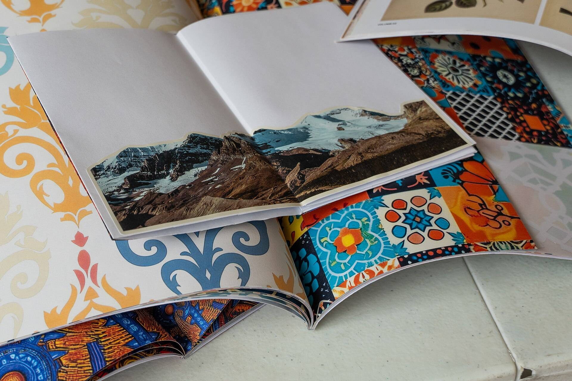 An open handmade zine lying on a pile of patterned papers