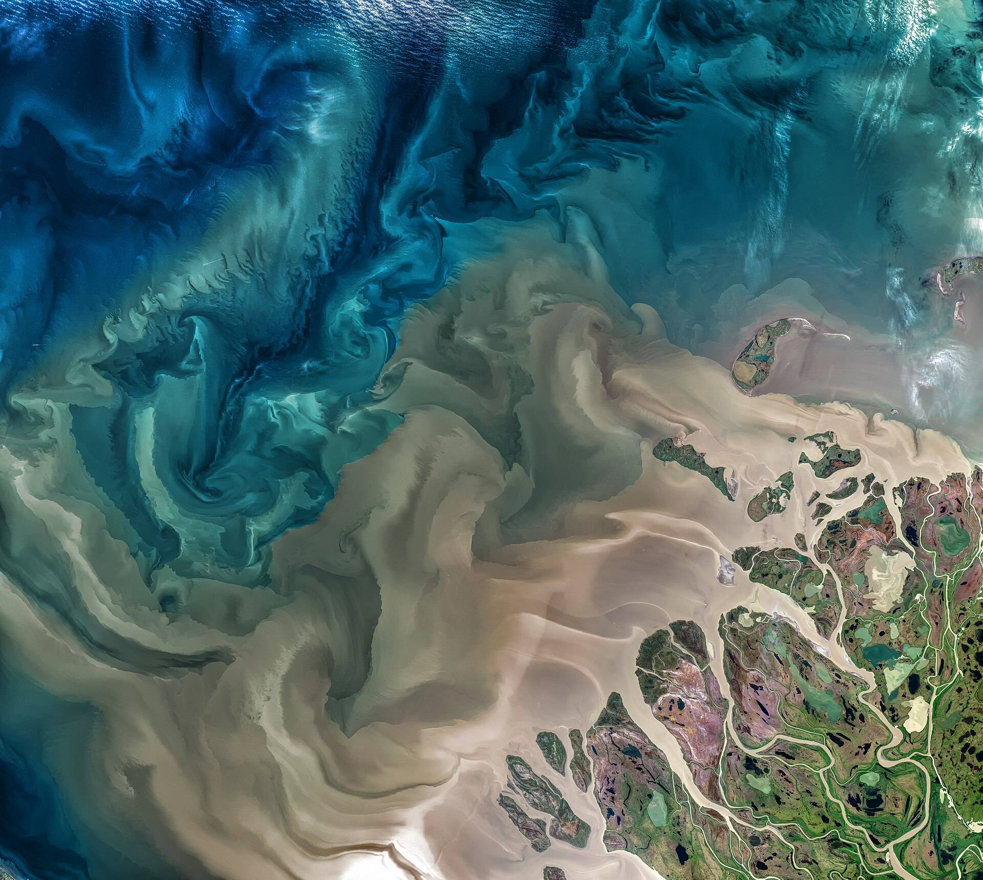 Silt from a river mouth swirling into the sea, seen straight down