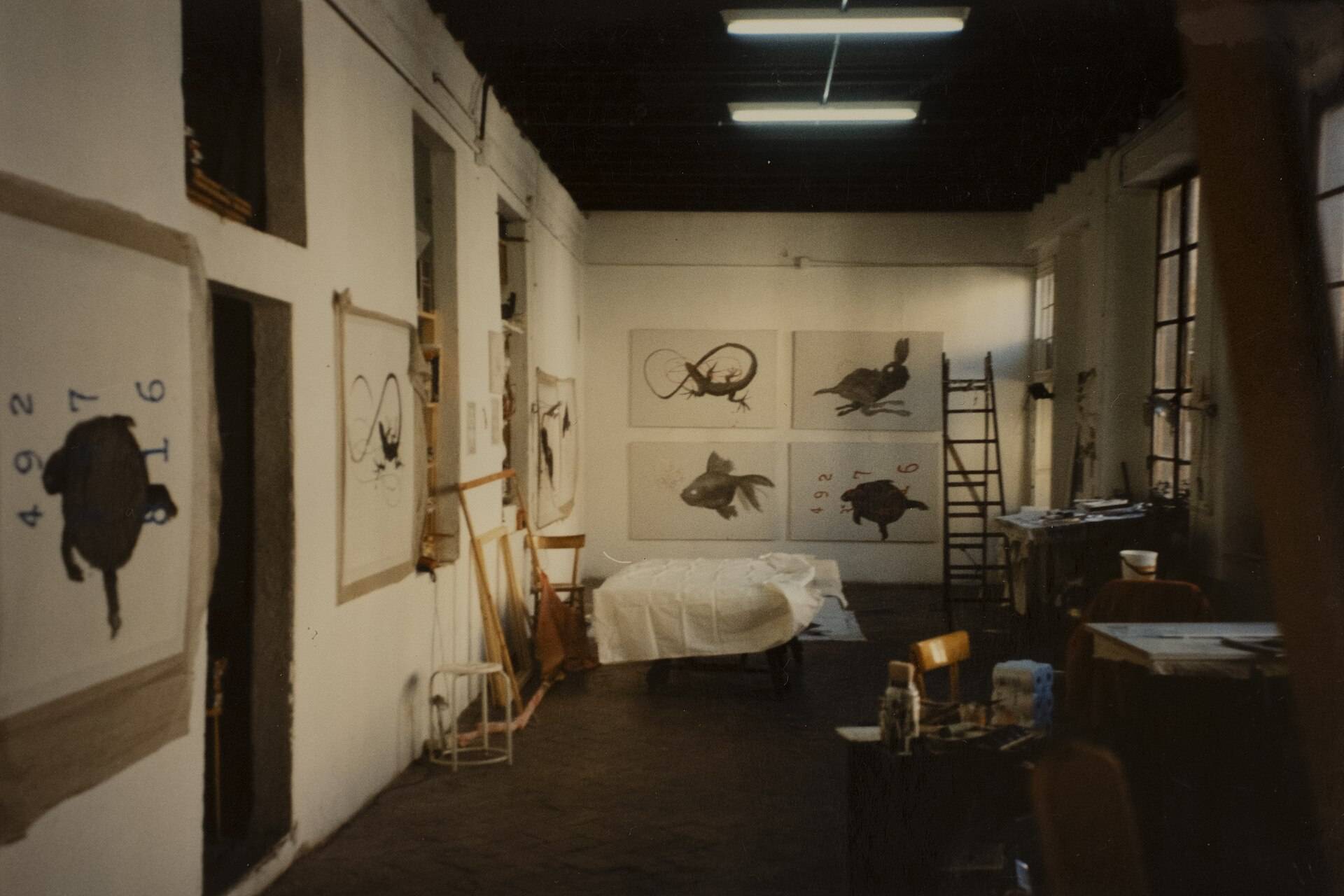 A whitewashed studio with large prints pinned along its walls
