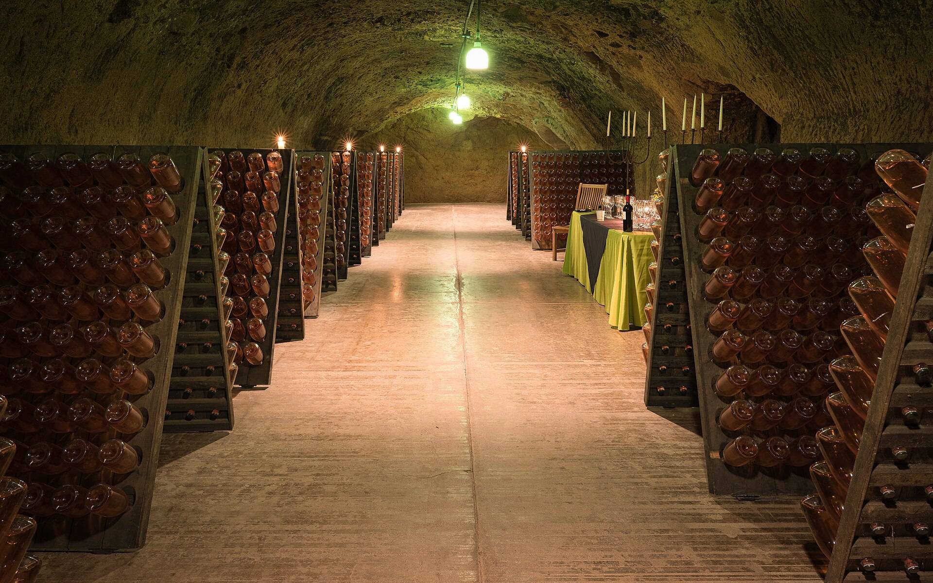 A long cellar aisle between racks of bottles laid neck down