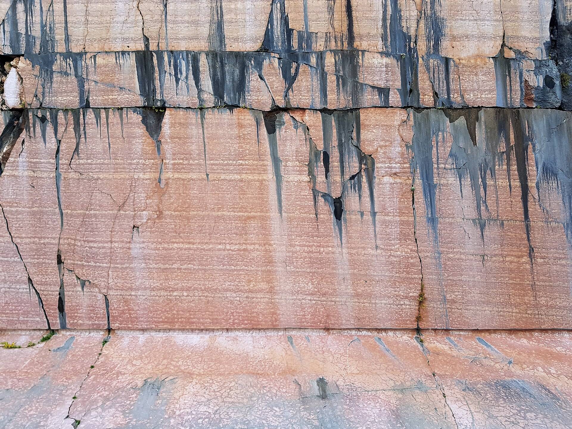 A sawn face of rose-red marble, banded in pale lines