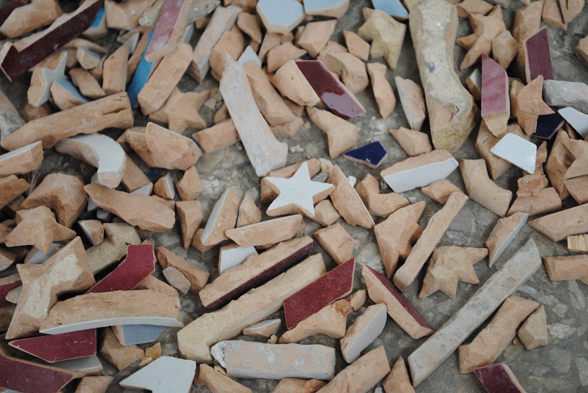 Loose pieces of terracotta and glazed tile in cream, wine and blue
