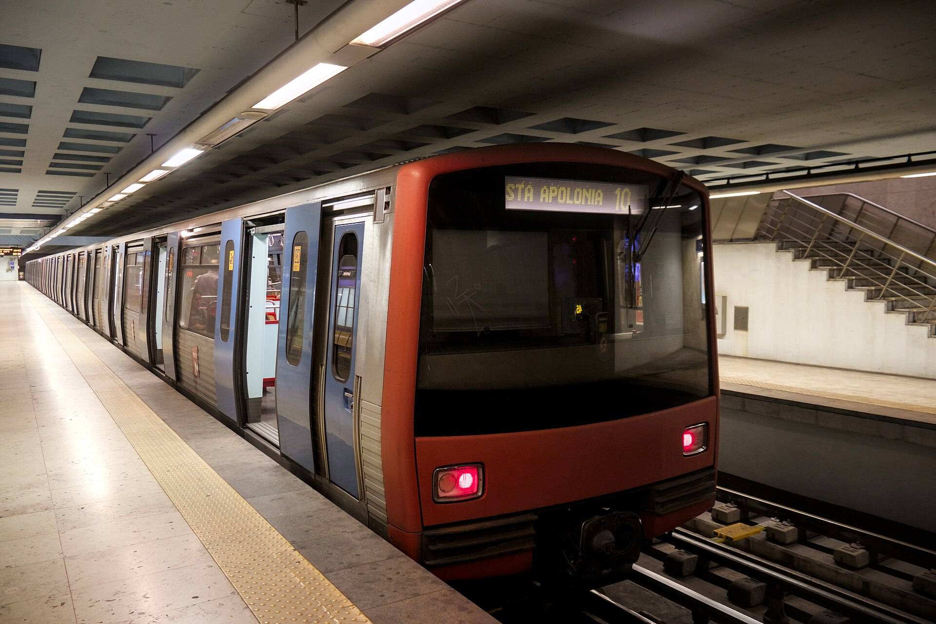 A red-fronted Lisbon metro train waiting at a pale platform, its sign set for Santa Apolónia